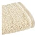 A white hand towel with a beige trim.