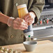 A person using a San Jamar sauce bottle to pour liquid into a bowl.