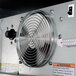The interior of a Beverage-Air back bar refrigerator with a thermometer and metal fan.