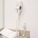 A Conair white wall mount hair dryer in a white bathroom.