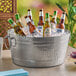 An American Metalcraft double wall party tub filled with beer bottles on a table outside.