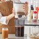 A woman using the Toddy Cold Brew System to pour coffee into a glass.