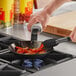 A person cooking food in a Choice carbon steel fry pan on a stove.