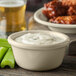 A white bowl of dip with celery sticks on a table.