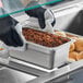 A person in black gloves using a white towel to hold a Choice stainless steel steam table pan filled with food.