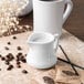 A white Carlisle plastic creamer pitcher with a handle.