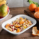 A white Carlisle rectangular bowl filled with oranges and pears on a table.