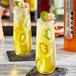 Two glasses of SHOTT Gold Kiwifruit syrup and lemonade with fruit slices on top.