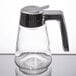 A Tablecraft glass syrup dispenser with a metal handle.