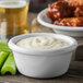A white Carlisle ramekin filled with white sauce on a white background.