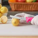 A hand in a glove holding a Choice knife with a neon pink handle to cut a lemon.