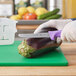 A person in gloves cutting an eggplant with a Choice purple handled utility knife.