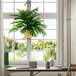 An LCG Sales artificial Phoenix Palm in a natural hanging basket hanging in front of a window with a wooden chair and desk.