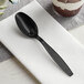 A Choice black plastic teaspoon on a napkin.