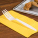 A white plastic fork on a yellow napkin.