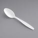 A white plastic teaspoon on a gray surface.