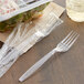 A clear plastic wrapped Choice heavy weight plastic fork next to a plastic container of salad.