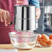 A person using a Choice stainless steel flour sifter to sift flour into a bowl.