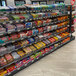 A Wanzl double-sided gondola shelf holding candy bars in a store.