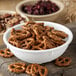 A white Carlisle chowder bowl filled with pretzels and nuts on a table.