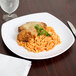 A plate of spaghetti and chicken with gravy on a Carlisle white square melamine plate.