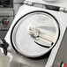 A close up of a Hobart stainless steel slicing plate with a circular blade.