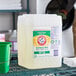 A white container of Arm & Hammer Free & Clear liquid laundry detergent with a green lid on a metal rack.