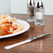 A plate of pasta and a WNA Comet stainless steel look plastic knife on a table.