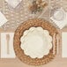 A table setting with a white plate, Sophistiplate Cream Scalloped Edge Paper Guest Towel, and a knife.