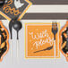 Sophistiplate Bella Black / White plastic cutlery in a bag on a table with black and orange plates.