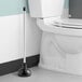 A white Lavex toilet plunger next to a white toilet.