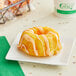 An individually wrapped Ne-Mo's Bakery orange dreamswirl bundt cake on a white plate.