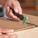 A hand holding a Klever Kutter EcoXChange box cutter and cutting a cardboard box.
