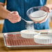 A person pouring Golden Barrel extra-fine granulated sugar into a white bowl.