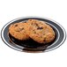 A black Fineline plastic plate with silver bands holding two chocolate chip cookies.