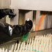 A pair of black neoprene shoulder-length gloves with cotton lining being worn by a person cleaning industrial equipment.