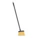 A Carlisle lobby broom with a long black handle and yellow flagged bristles.