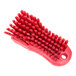 A Carlisle red handheld scrub brush with many bristles.