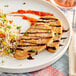 A white plate with Eat Meati Plant-Based Classic Cutlet served with couscous and rice.