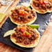 A group of tacos with Abbot's Butcher plant-based vegan ground beef, tomatoes, and meat on a black plate.