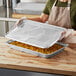 A woman holding a Choice aluminum foil steam table pan full of food.