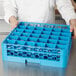 A chef using a Carlisle glass rack extender to hold many glasses in a blue tray.