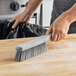 A hand using a Carlisle Sparta soft polyester counter brush to clean a counter.