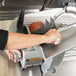 A person using a Hobart meat slicer to cut meat on a counter.