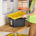 A woman in a yellow vest putting a yellow lid on a black Tough Box.