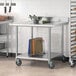A Regency stainless steel work table with an undershelf and casters holding a bowl of vegetables.