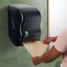 A woman using a black San Jamar Tear-N-Dry paper towel dispenser.