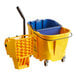 A yellow Carlisle OmniFit mop bucket on wheels with a blue mop inside.