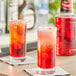 Two glasses of Finest Call grenadine on a table in a cocktail bar.