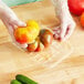 A person in gloves holding a tomato in a CKF clear plastic meat tray.